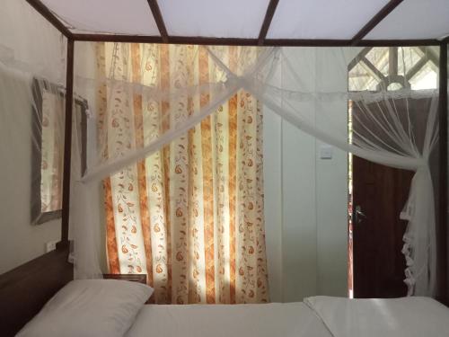 a bedroom with a bed and a window with curtains at Sigiriya Nature View home Stay in Sigiriya