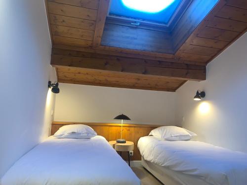 two beds in a room with a ceiling at La Résidence de L'Ours in Megève