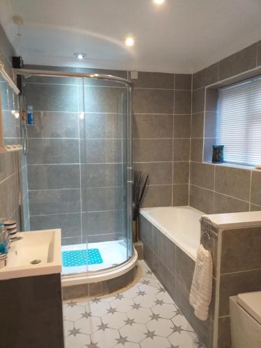 a bathroom with a shower and a tub and a sink at Crow Corner in Yoxford