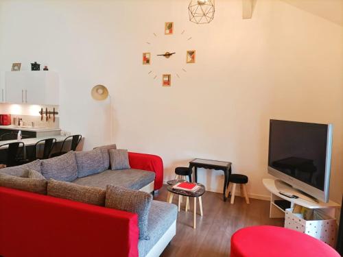 Il comprend un salon doté d'un canapé rouge et d'une télévision à écran plat. dans l'établissement Superbe appartement type loft en duplex rue Buat, à Châlons-en-Champagne