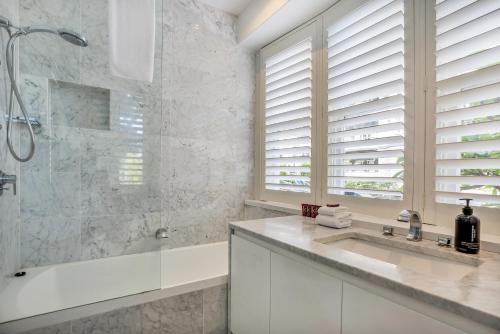 a white bathroom with a shower and a sink at Premium Double Bay 3 bedroom apartment in Sydney