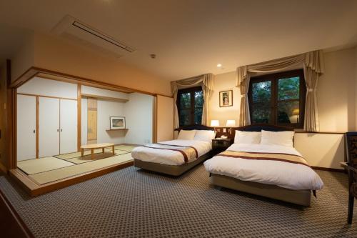 a bedroom with two beds and a window at 伊豆高原温泉ホテル 森の泉 in Ito