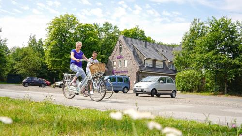 格羅瑙的住宿－dS Hotel Restaurant Gronau，一名妇女骑着自行车,带着孩子在篮子里