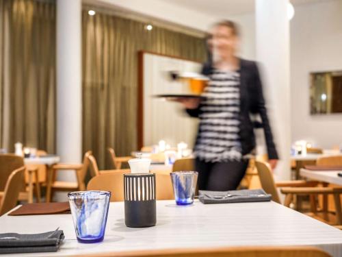 a woman holding a plate of food on a table at Sydney Central Hotel managed by The Ascott Limited in Sydney