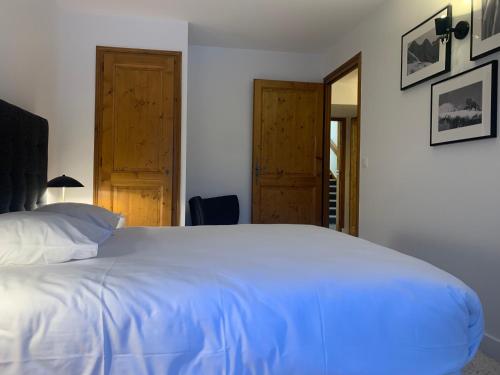 a bedroom with a large white bed and two doors at La Résidence de L'Ours in Megève