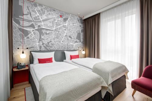 two beds in a hotel room with a map on the wall at IntercityHotel Dortmund in Dortmund