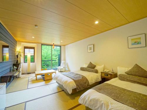 a hotel room with two beds and a living room at 伊豆高原温泉ホテル 森の泉 in Ito