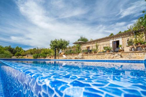 a swimming pool with blue water in front of a house at Can Pulit in Selva