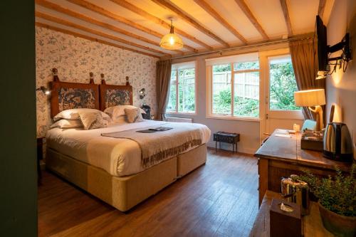 a bedroom with a bed and a desk and windows at Castle Inn in West Lulworth