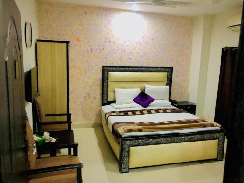 a bedroom with a bed with a purple pillow at Hotel Tulip Inn in Lahore