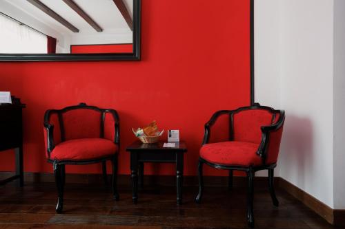 two chairs and a table in a room with a red wall at Conacul Archia in Deva