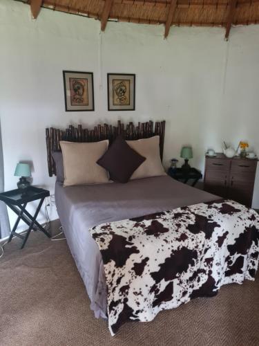 a bed with a black and white blanket on it at Swallowfield Rondavels in Champagne Valley