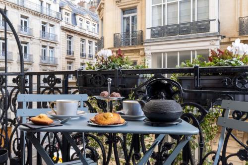 stół z filiżankami herbaty i ciastkami na balkonie w obiekcie Hotel West-End w Paryżu