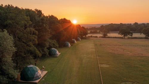 a group of tents in a field at sunset at Camp Kátur Glamping in Carthorpe