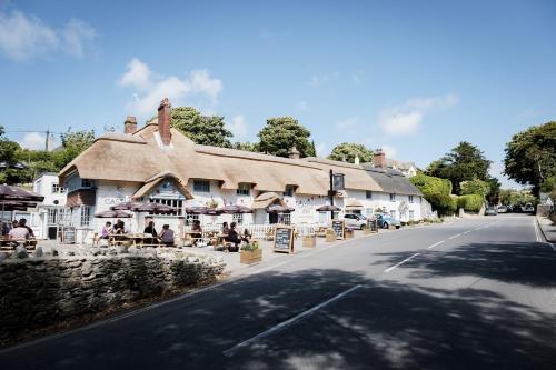 a building with tables and umbrellas on the side of a road at Castle Inn in West Lulworth