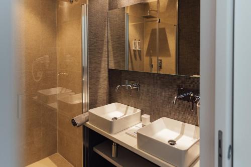 a bathroom with two sinks and a glass shower at BN SUITES Teatro in Alicante