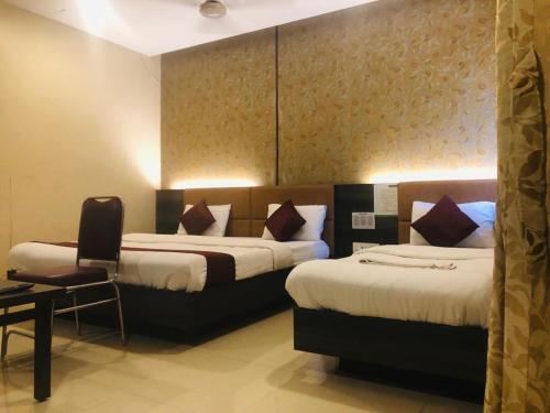 una habitación de hotel con 2 camas y una silla en HOTEL SHARADA INTERNATIONAL en Thane