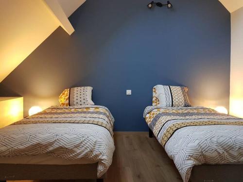 Dos camas en una habitación con una pared azul. en Gite du Cours St Mauris Authentique et moderne, en Dole