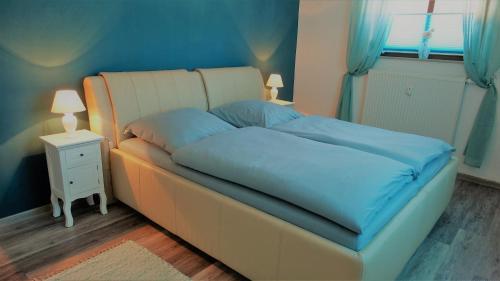 a bedroom with a bed with blue sheets and a window at Villa Moser - Ferienwohnung mit Terrasse in Gera