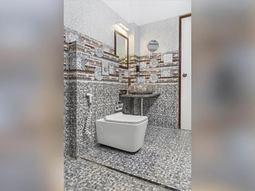 a bathroom with a toilet and a mosaic wall at Kanishka Retreat Resort Chail in Chail
