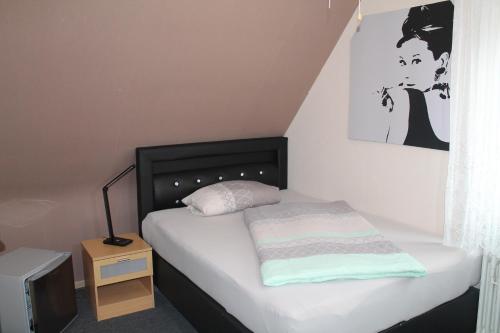 a small bedroom with a bed with a black headboard at Gasthaus Zur Sonne in Freiburg im Breisgau