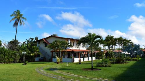 een huis met palmbomen en een groene tuin bij Hotel Pousada Rancho Fundo in Camaçari