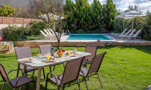 a table and chairs in a yard next to a pool at Villa Lucas in Melidhónion