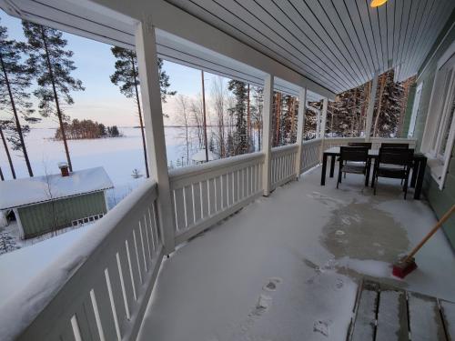 a porch covered in snow with a table and chairs at Lake Cottage Jänisvaara in Kolinkylä