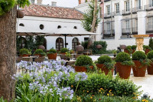 a garden with flowers and tables and an umbrella at Palacio de los Duques Gran Meliá - The Leading Hotels of the World in Madrid