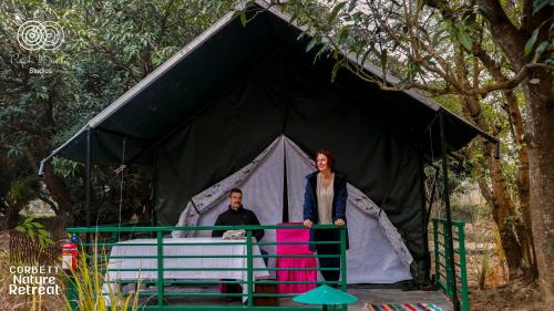 a man and a woman standing in a tent at Corbett Nature Retreat in Rāmnagar