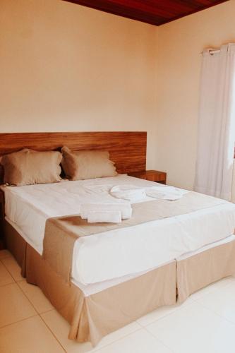 a bedroom with a large bed with towels on it at Pousada Encantos de Palmeiras in Palmeiras