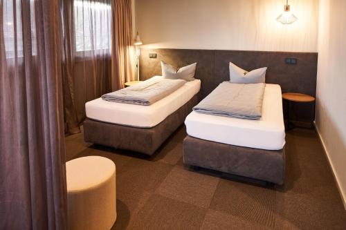 a hotel room with two beds and a chair at Novitel Hotel Kirchheim - München Messe in Kirchheim