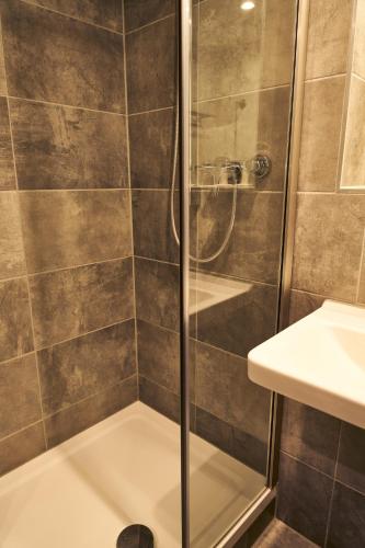 a shower with a glass door in a bathroom at Novitel Hotel Kirchheim - München Messe in Kirchheim