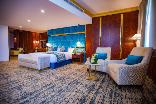 a hotel room with a bed and two chairs at Le Park Concord Hotel & Resident Najran in Najran