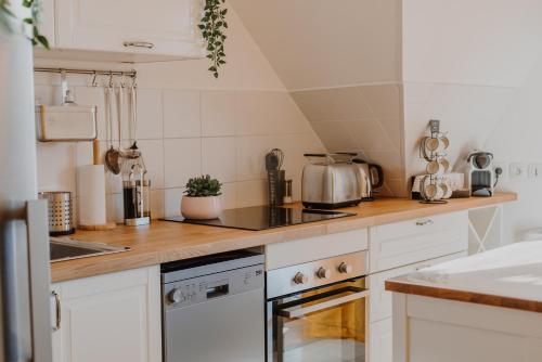 une cuisine avec des armoires blanches et des appareils électroménagers blancs dans l'établissement Appartement 2 chambres aux portes de Deauville 100m du Pôle International du cheval, à Saint-Arnoult