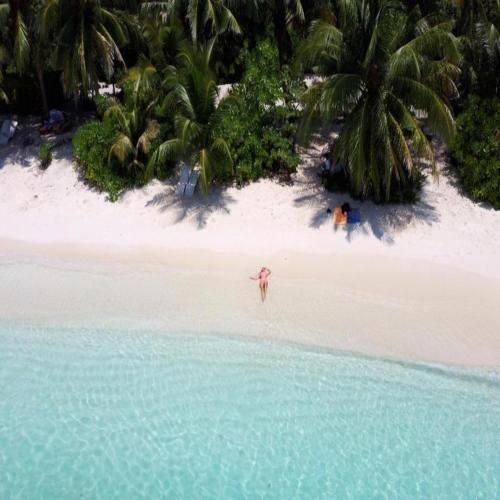 a person standing on a beach in the water at Thoddoo Haisha inn, Maldives in Thoddoo