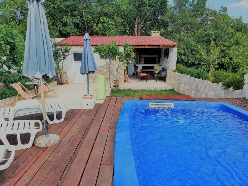 - une piscine sur une terrasse en bois avec des parasols dans l'établissement Apartman Gizdavac, à Gizdavac
