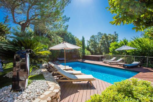 - une piscine bordée de chaises longues et de parasols dans l'établissement VILLA JUSTINE VI4239 By Riviera Holiday Homes, à Mandelieu-la-Napoule