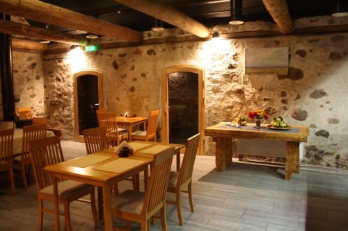a restaurant with wooden tables and chairs and stone walls at Rēderi in Roja