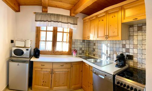 cocina con armarios de madera, fregadero y microondas en BorászPorta en Villány