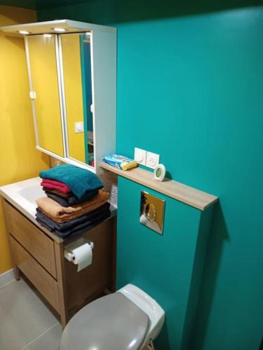 une salle de bain avec toilettes et un mur bleu dans l'établissement Le Madison 2, à Châteauroux