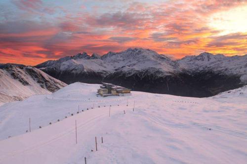 a ski lodge on a snow covered mountain with a sunset at Wallackhaus RegioJet Hotels in Heiligenblut
