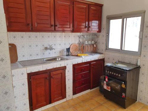 a kitchen with red cabinets and a sink and a stove at Appartement chic au quartier Omnisport in Yaoundé