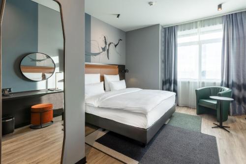 a hotel room with a bed and a mirror at TITANIC Comfort Kurfürstendamm in Berlin
