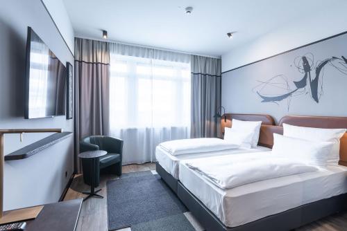 a hotel room with two beds and a window at TITANIC Comfort Kurfürstendamm in Berlin