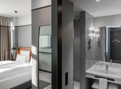 a hotel room with a bed and a sink at TITANIC Comfort Kurfürstendamm in Berlin