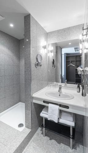 a bathroom with a sink and a mirror and a tub at TITANIC Comfort Kurfürstendamm in Berlin