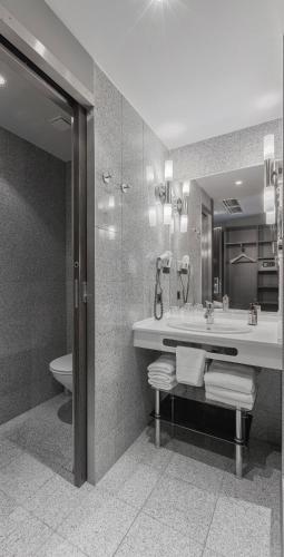a bathroom with a sink and a toilet and a mirror at TITANIC Comfort Kurfürstendamm in Berlin