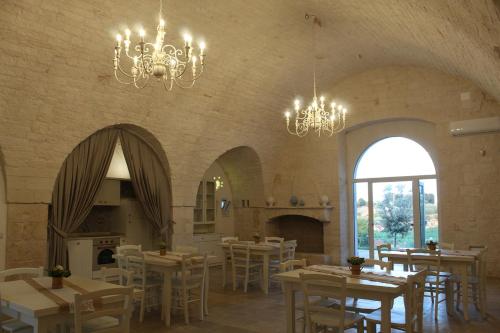 a dining room with tables and chairs and chandeliers at Trulli Arco Antico in Locorotondo