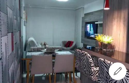 uma sala de estar com uma mesa e cadeiras e uma televisão em Apartamento aconchegante em Bento Gonçalves, próximo ao vale dos vinhedos em Bento Gonçalves